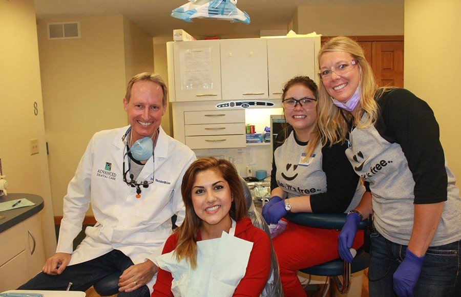 Smiling patient denetist and two team members in treatment room