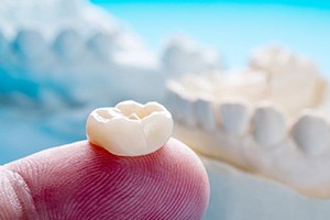 Tooth-colored dental crown on fingertip