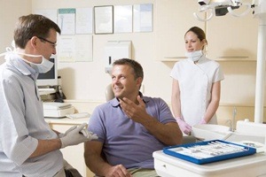 Man in dental chair talking to dentist