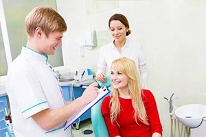 Young woman in dental chair talking to dentist