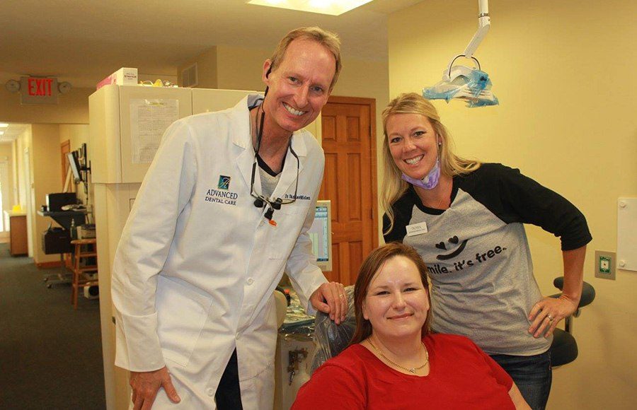 Smiling dentist assistant and patient in exam room