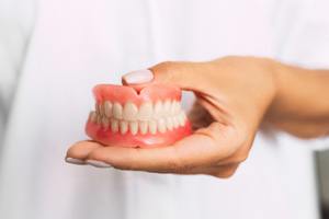 : dentist holding dentures 