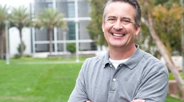 man smiling outside with arms crossed