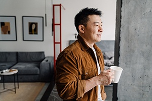 a smiling man looking out of his apartment window