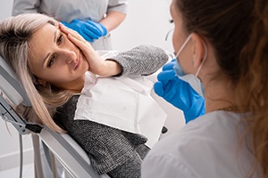 a woman holding her mouth and speaking with a dentist