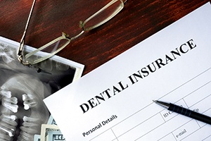 Top of dental insurance form with pen, glasses, and X-rays