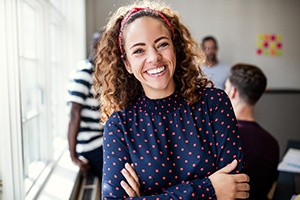 A young female wearing a navy and pink polka dot blouse smiling after receiving a tooth-colored filling