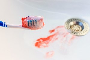 toothbrush with blood on it sitting in a bathroom sink