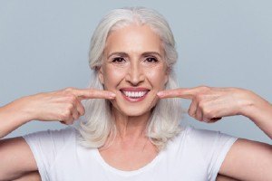 Older woman pointing to beautiful smile