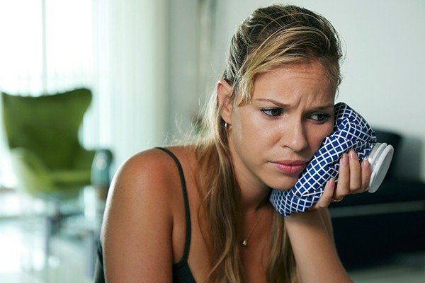 woman holding ice pack to her cheek