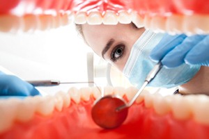 A dentist examining gum tissue with a dental mirror.