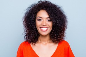 Women with white, straight teeth smiling in red shirt