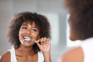 Woman smiling while brushing her teeth