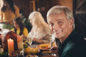 Man smiling at dinner table with family blurred in the background