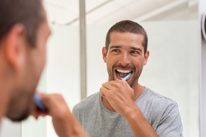 man brushing his teeth in the mirror