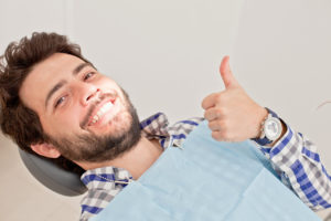 Young man at dental checkup giving thumbs up sign