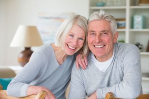 senior man and woman showing off their dental implants by smiling