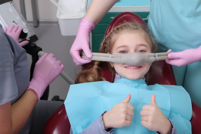 Girl at dentist thumbs up.