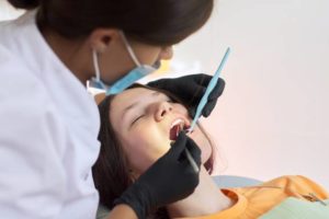 Dentist looking in the mouth of sedated female patient