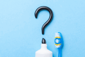 Charcoal toothpaste forming a question mark on a blue background
